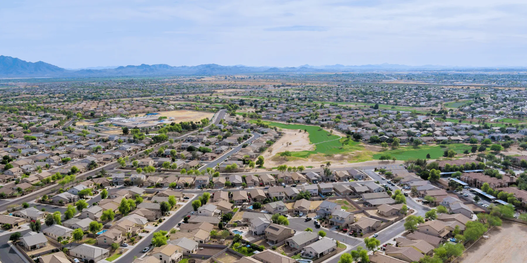 Aerial view of a sprawling suburban neighborhood with mountains in the distance.