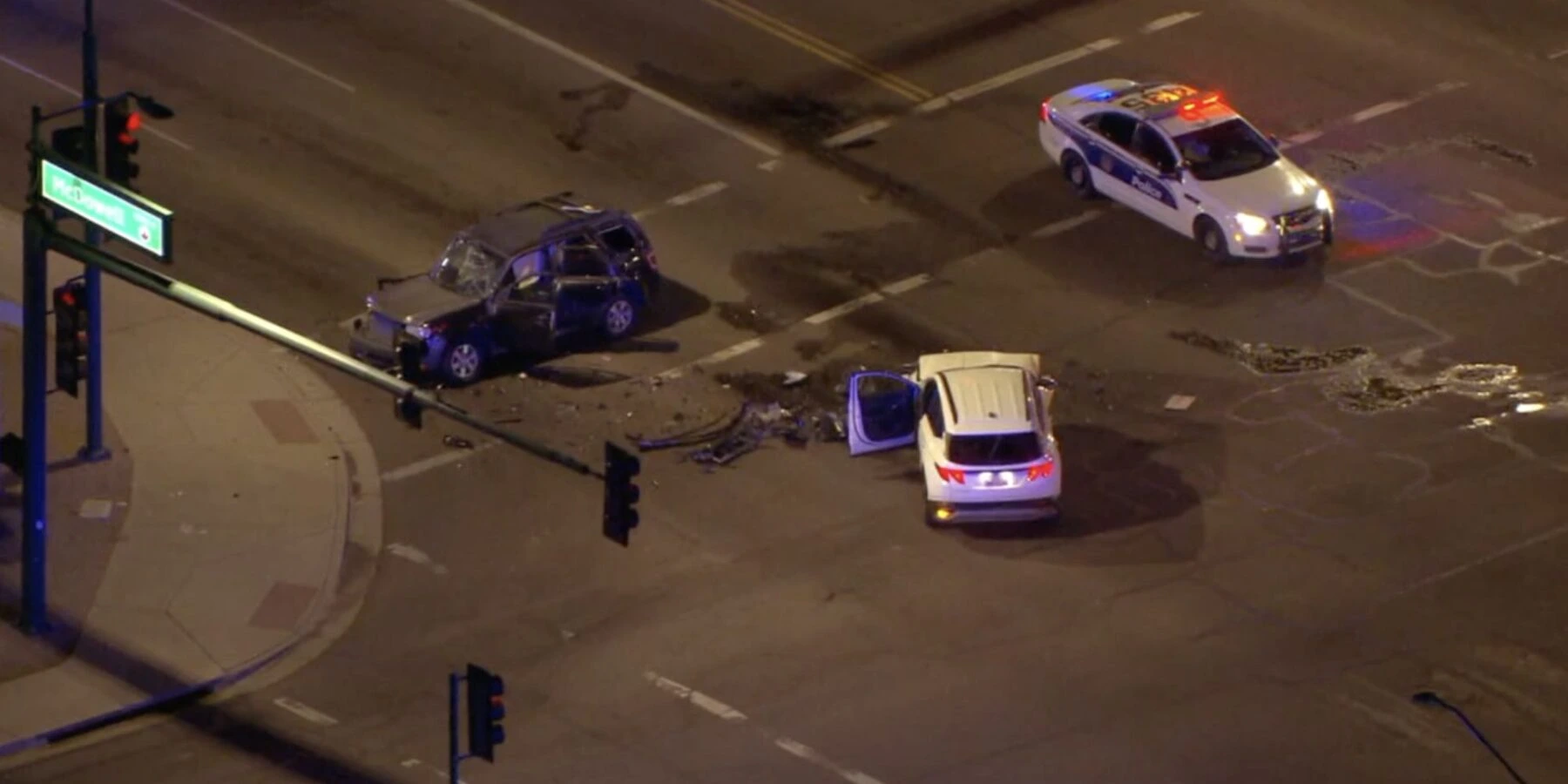 Overhead night view of a two-car accident at an intersection with a police cruiser on the scene.