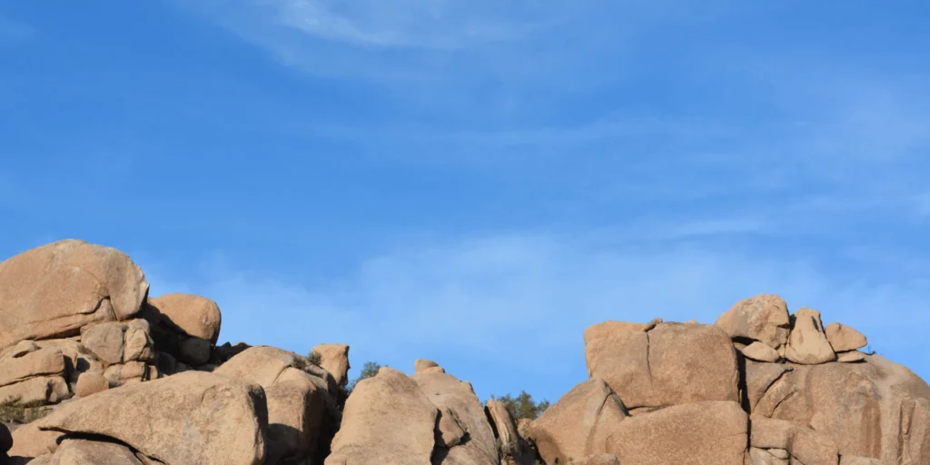 Large, rounded desert rock formations under a bright blue sky with light, wispy clouds.