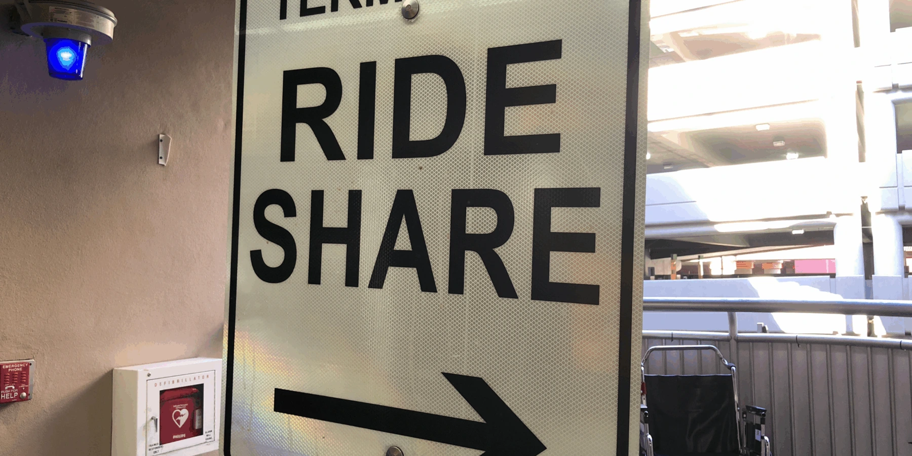 Close-up of an airport sign reading "RIDE SHARE" with an arrow pointing right.